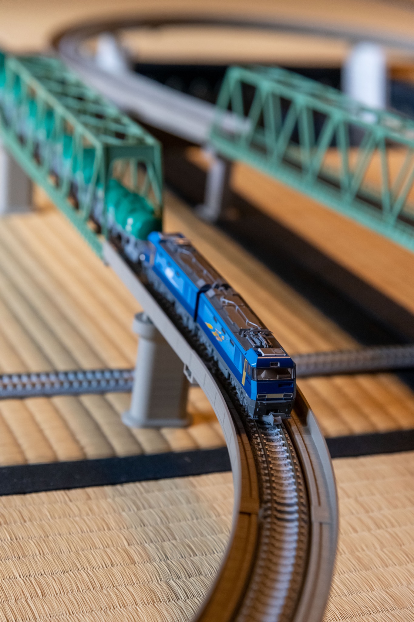 Model freight locomotive crossing a green railway bridge